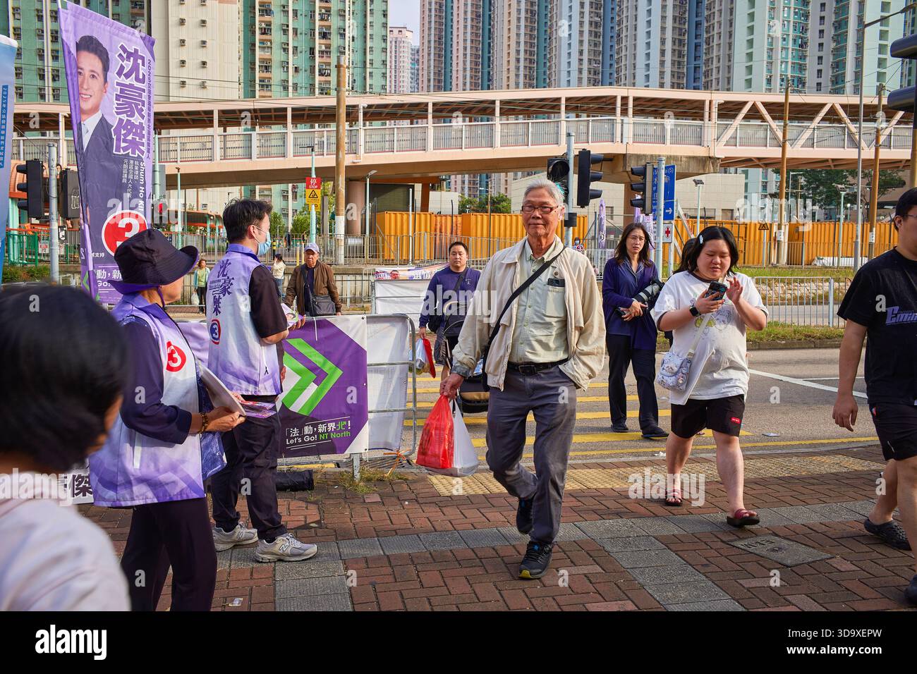 Hongkong, China. Dezember 2025. Der Kandidat verteilt Flugblätter an den Passanten in der Nähe eines Wahlzentrums in Tin Shui Wai. Die Parlamentswahlen 2025 in Hongkong finden am 7. Dezember 2025 statt, um die 90 Mitglieder des 8. Hongkonger Legislativrates zu wählen. Quelle: SOPA Images Limited/Alamy Live News Stockfoto