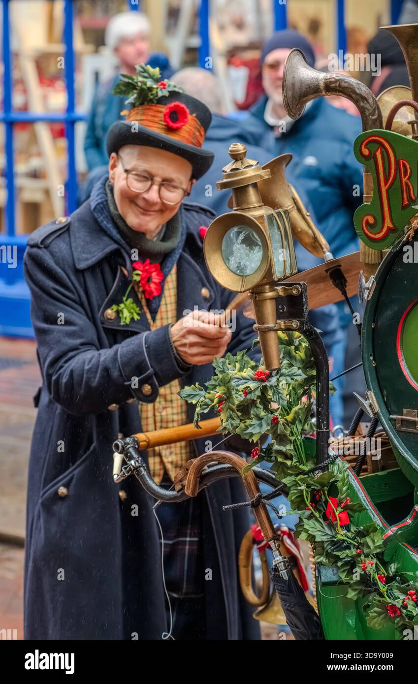 Dickens Christmas Festival Rochester UK Dezember 2025. Ein lächelnder Straßenkünstler in festlichem Oberhut spielt Schlagzeug auf einem dekorierten ein-Mann-Bandwagen. Stockfoto
