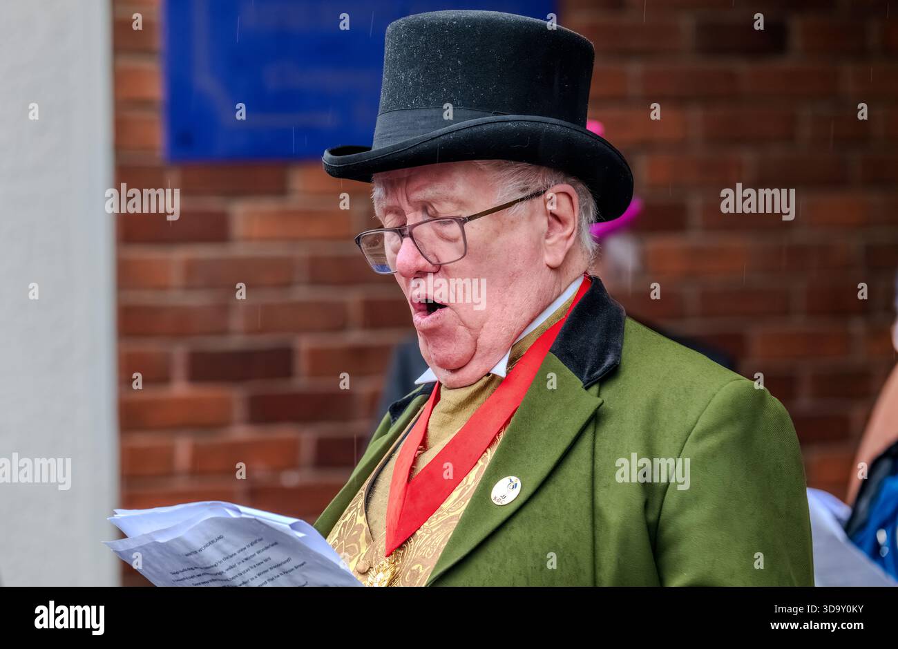 Dickens Christmas Festival Rochester UK Dezember 2025. Feierlicher Sprecher in traditioneller Kleidung mit Hut, Band und Zeitungen bei öffentlichen Veranstaltungen Stockfoto