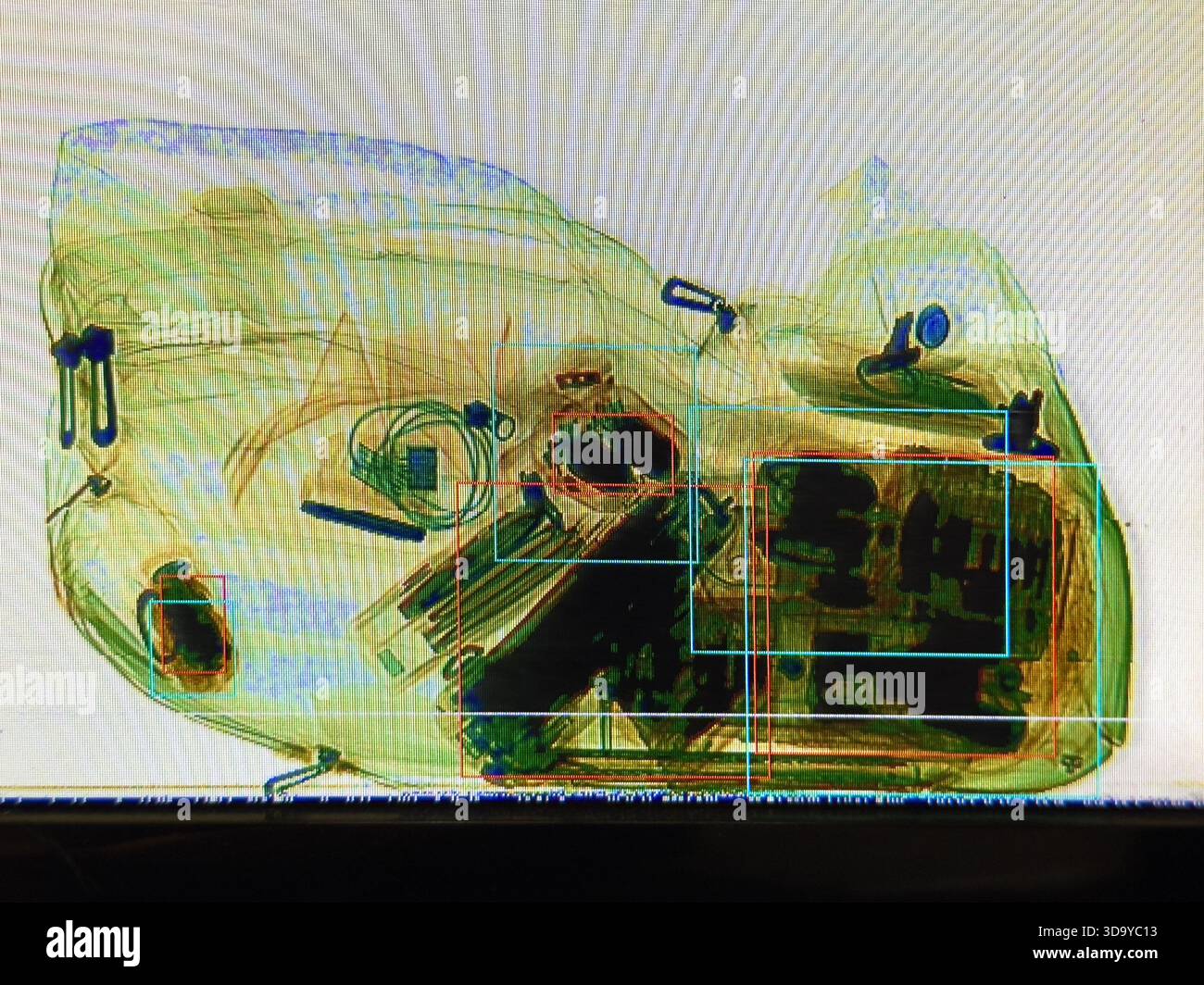 Röntgenaufnahme einer Reisetasche zur Flughafensicherheit, in der Kleidung und persönliche Gegenstände aus verschiedenen Elektronikgeräten durch Erkennungsboxen auf dem Überwachungsbildschirm hervorgehoben werden Stockfoto