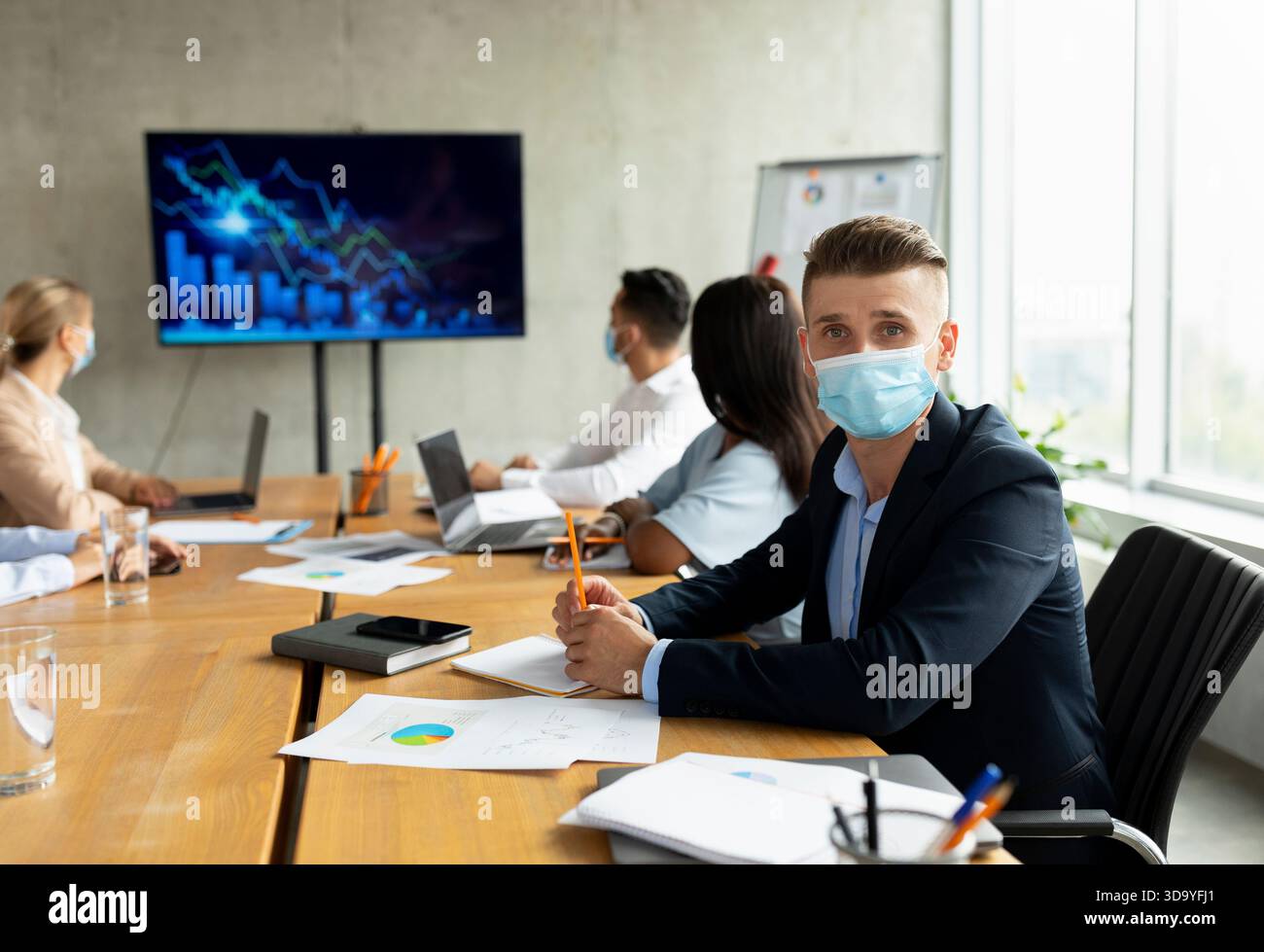 Multiethnisches Business-Team in Masken, das während der Gesundheitskrise im Büro zusammenarbeitet Stockfoto
