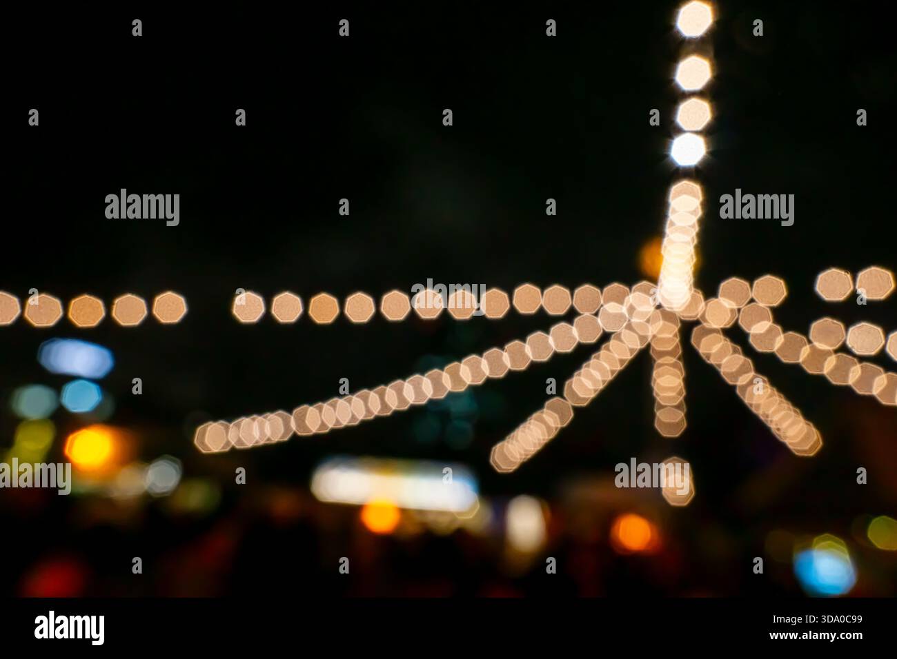 Unscharfe Lichterketten auf einem Messe- oder Weihnachtsmarkt, in horizontaler Ausrichtung mit starkem Bokeh-Effekt erfasst. Stockfoto