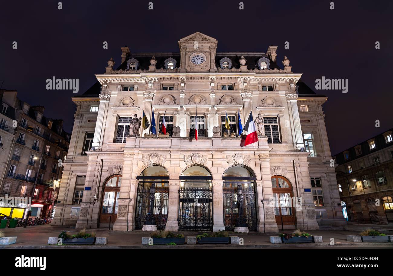 Rathaus des 18. Arrondissements in Paris, Frankreich. Das historische Gebäude mit Uhrenturm und Fahnen steht nachts am Place Jules Joffrin Stockfoto