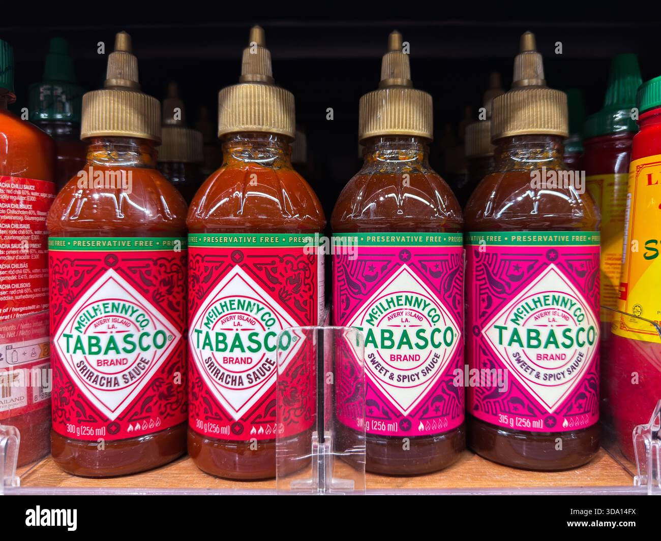 Penang, Malaysia - 7. Juli 2025: Vier Flaschen Sriracha-Sauce der Marke Tabasco werden in einem Lebensmittelgeschäft ausgestellt. Jede Flasche enthält unterschiedliche Verpackungen Stockfoto