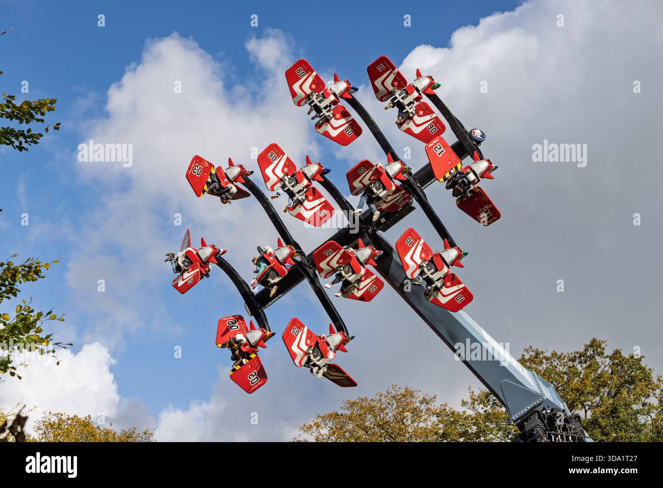 Im Vergnügungspark Duinrell in Wassenaar, Niederlande, reiten die Menschen in Flugzeugen auf den Wild Wings vor einem blauen Himmel. Stockfoto