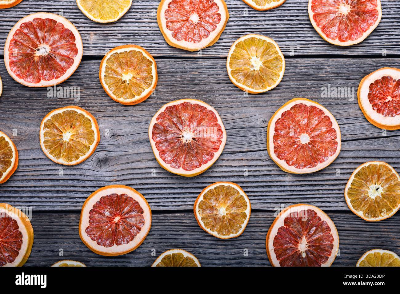 Blick von oben auf getrocknete Orangen- und Grapefruitscheiben auf rustikalem Holzbrett. Weihnachten oder Neujahr Ornament Border Hintergrund Stockfoto