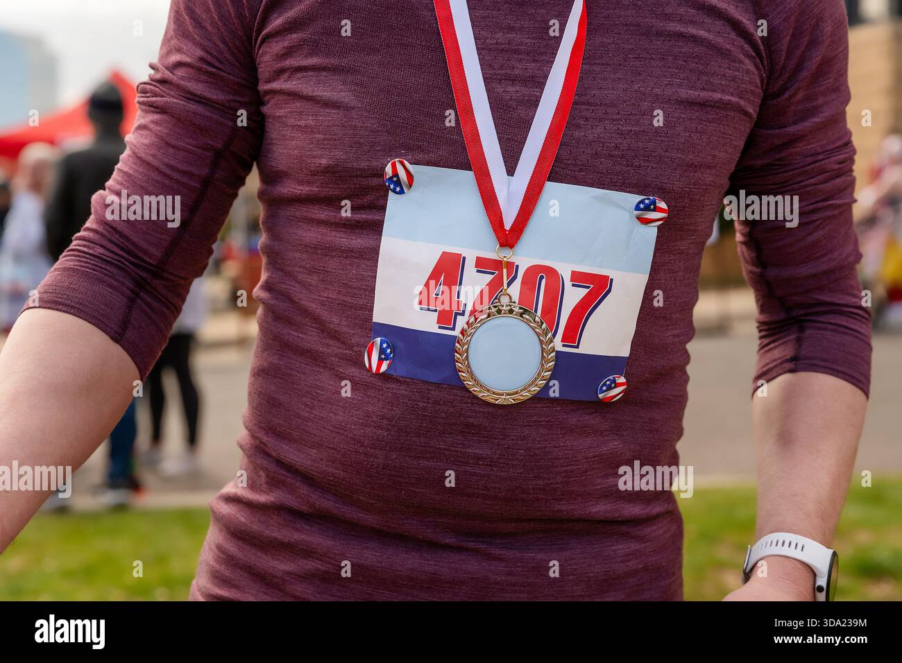 Männlicher Läufer trägt nach dem Ende der Veranstaltung Lätzchen und Medaille Stockfoto