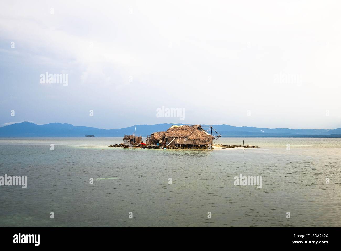 Eine Strohdachhütte auf Stelzen auf einer flachen Sandinsel Stockfoto