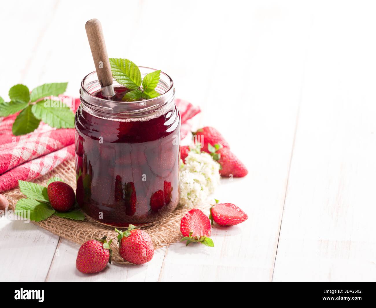 Nahaufnahme eines Glases Erdbeermarmelade mit frischen Erdbeeren auf dem Tisch Stockfoto