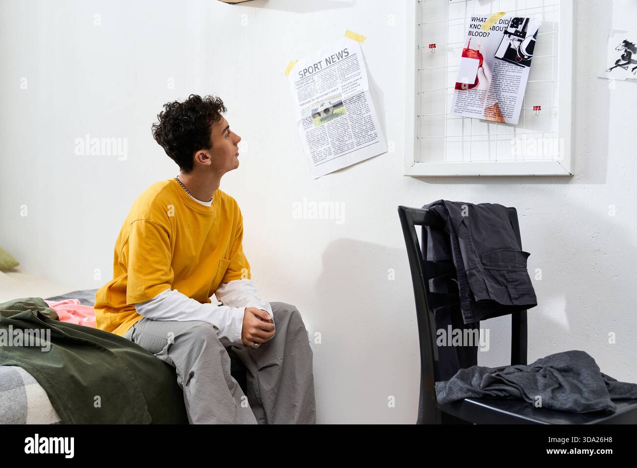 Ein stilvoller Teenager denkt tief nach, während er in seinem Zimmer von persönlichen Erinnerungsstücken umgeben ist. Stockfoto
