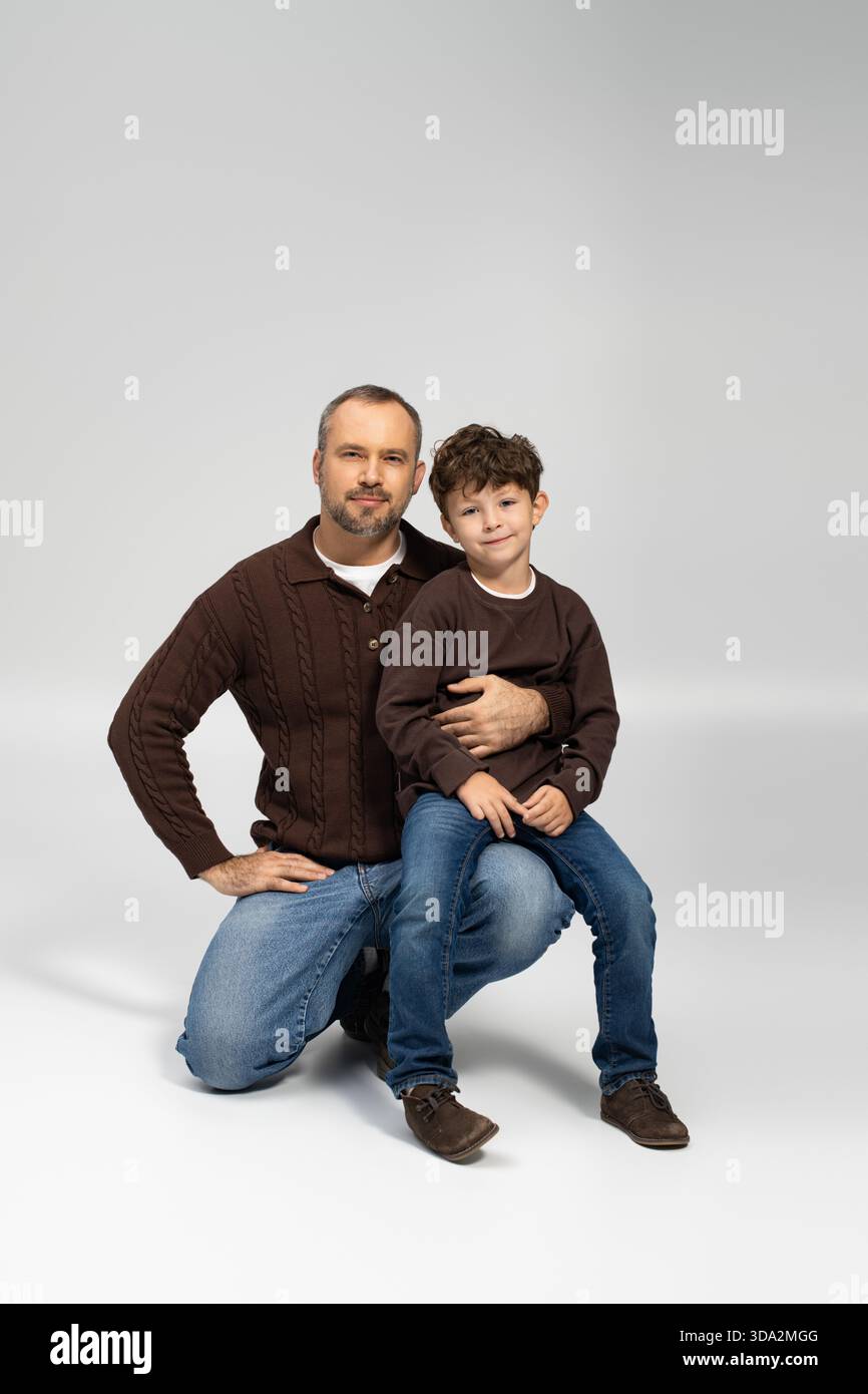 Ein Vater kniet mit seinem Sohn auf seinem Schoß und teilt sich einen liebevollen Moment drinnen. Stockfoto