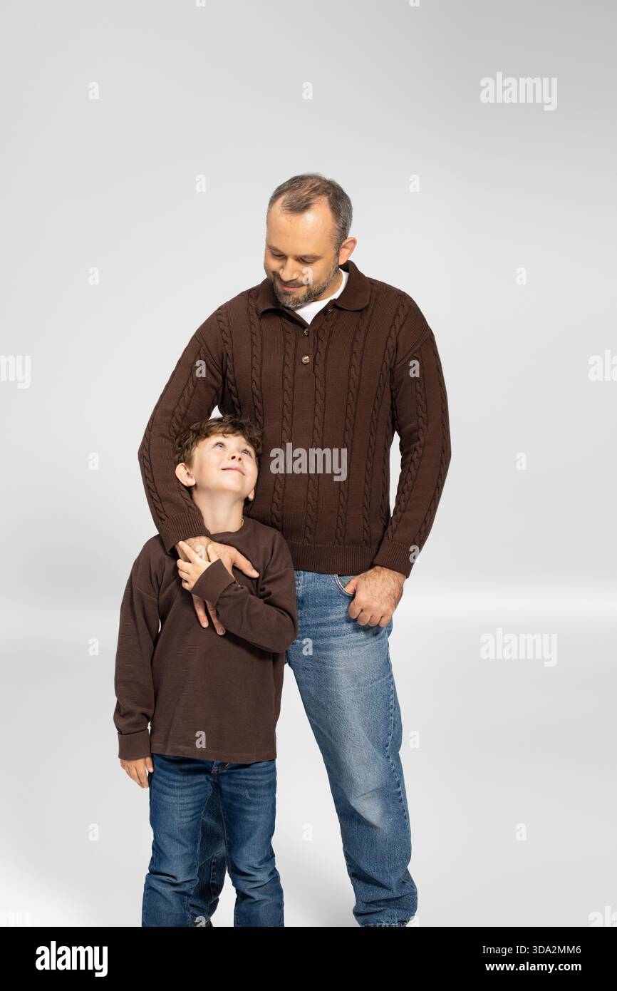 Ein Vater und ein Sohn in kuscheligen braunen Pullis teilen einen stolzen, liebevollen Moment zusammen. Stockfoto