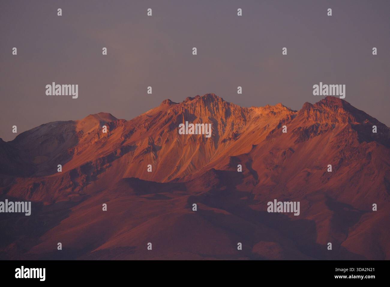 Sonnendurchflutete Berghänge in der Nähe von Arequipa mit warmem Abendlicht, das die zerklüfteten Felsformationen der Anden hervorhebt. Stockfoto
