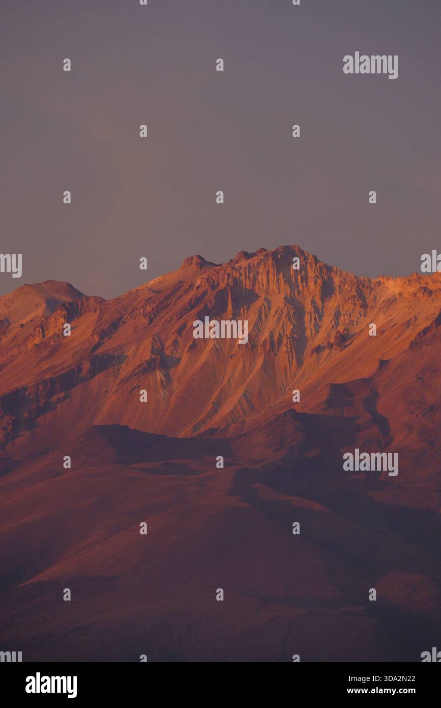 Sonnendurchflutete Berghänge in der Nähe von Arequipa mit warmem Abendlicht, das die zerklüfteten Felsformationen der Anden hervorhebt. Stockfoto