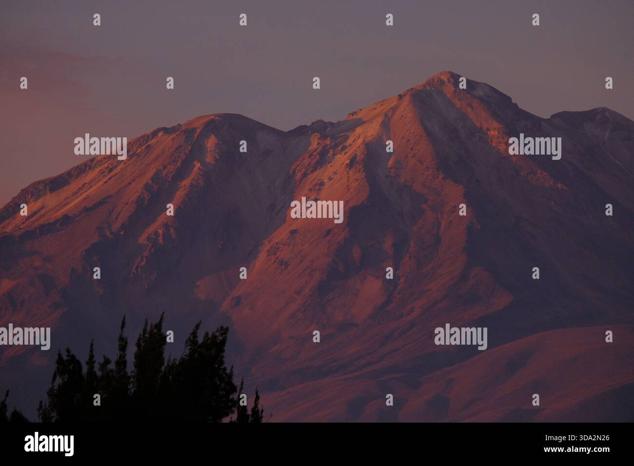 Sonnendurchflutete Berghänge in der Nähe von Arequipa mit warmem Abendlicht, das die zerklüfteten Felsformationen der Anden hervorhebt. Stockfoto