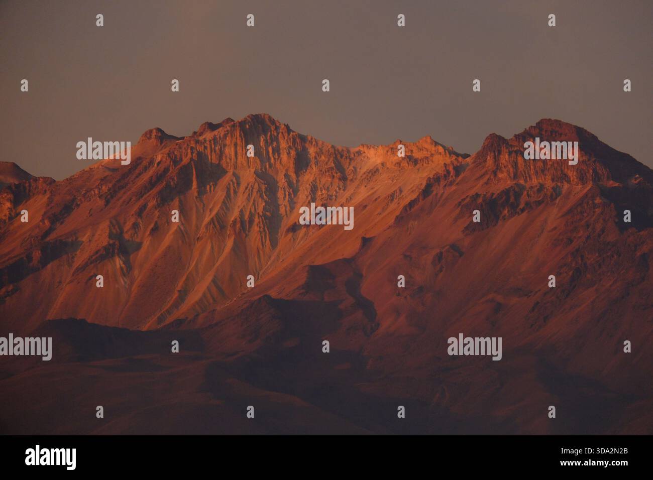 Sonnendurchflutete Berghänge in der Nähe von Arequipa mit warmem Abendlicht, das die zerklüfteten Felsformationen der Anden hervorhebt. Stockfoto