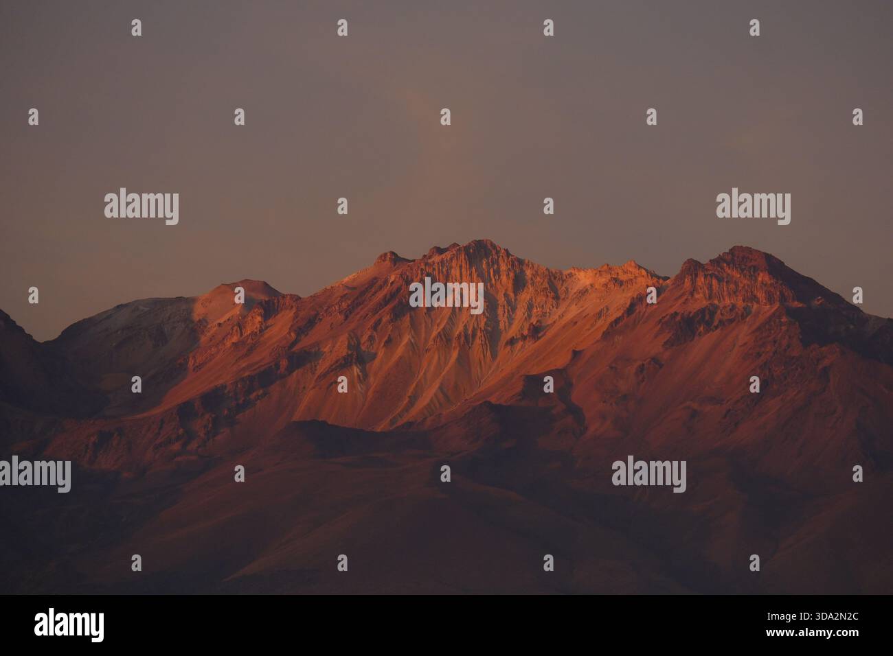 Sonnendurchflutete Berghänge in der Nähe von Arequipa mit warmem Abendlicht, das die zerklüfteten Felsformationen der Anden hervorhebt. Stockfoto