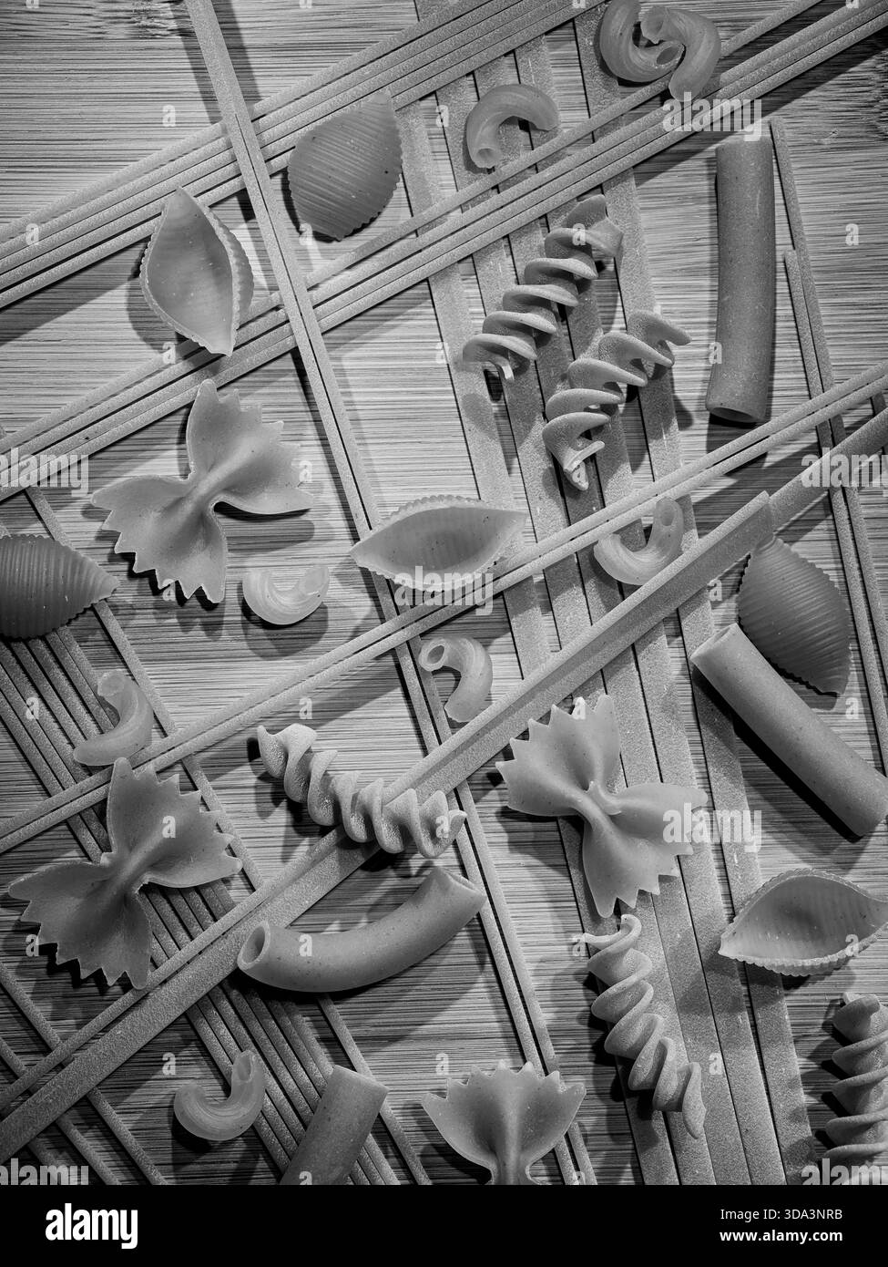 Eine schwarz-weiße Flatlay aus verschiedenen getrockneten Nudeln verteilt auf dem Tisch. Stockfoto