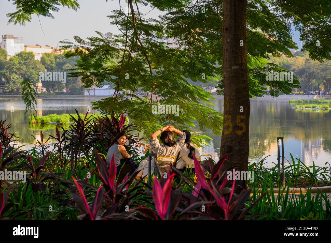 Vietnamesische Freunde unterhalten sich am Thien Quang See, Hanoi, Vietnam Stockfoto
