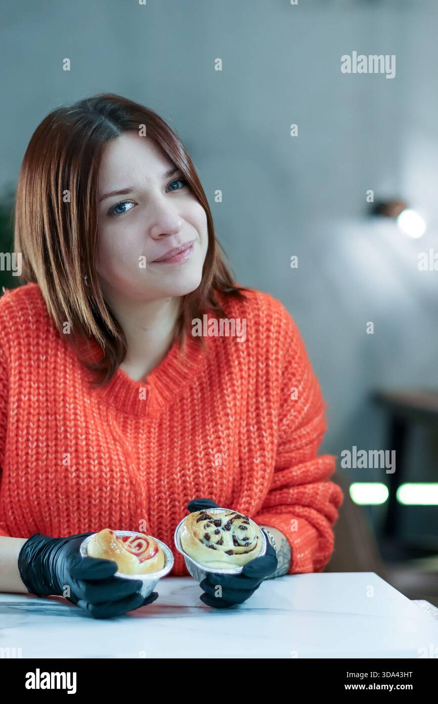 Innenporträt einer Person im Pullover, die Schokolade und Beerengebäck auf der Theke hält Stockfoto