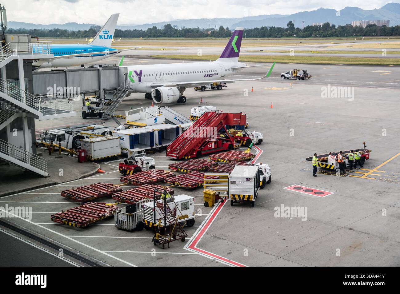 Auf dem Flughafengelände mit Verkehrsflugzeugen, Bodenbesatzung und Gepäckwagen an einem stark frequentierten Flughafenterminal, dem internationalen Flughafen El Dorado, Bogotá Stockfoto