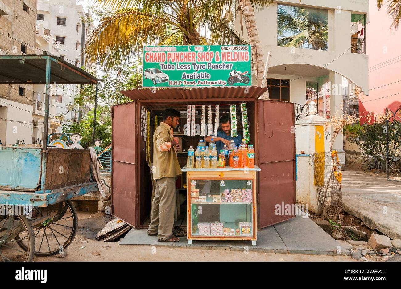 Puttaparthi, Andhra Pradesh, Indien - 11. Januar 2013: Kleiner Straßenladen, in dem Getränke, Zigaretten und kleine Artikel mit einem Verkäufer und einem Käufer in Putt verkauft werden Stockfoto