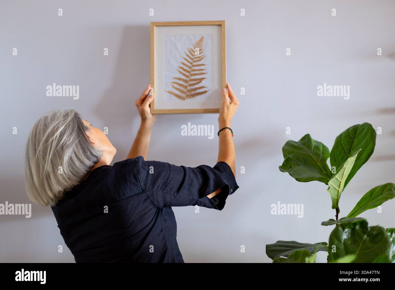 Der Innenarchitekt hängt mit einem wunderschön gerahmten botanischen Druck, der das moderne Haus mit einem erfrischenden Hauch von Natur und Eleganz aufwertet Stockfoto