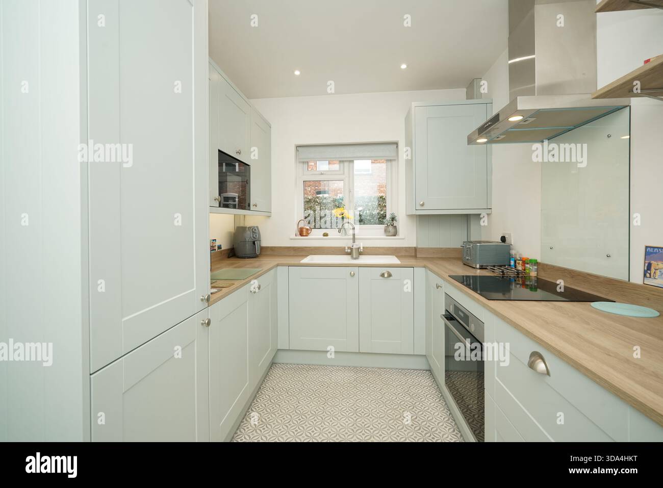 Moderne Küche mit Lichtschränken und einfachem Layout in einem Wohnhaus bei Tageslicht Stockfoto