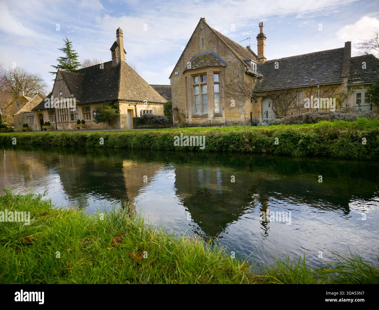 Historisches Stone Schoolhouse am Fluss – Cotswolds Village Reflection England Großbritannien Stockfoto