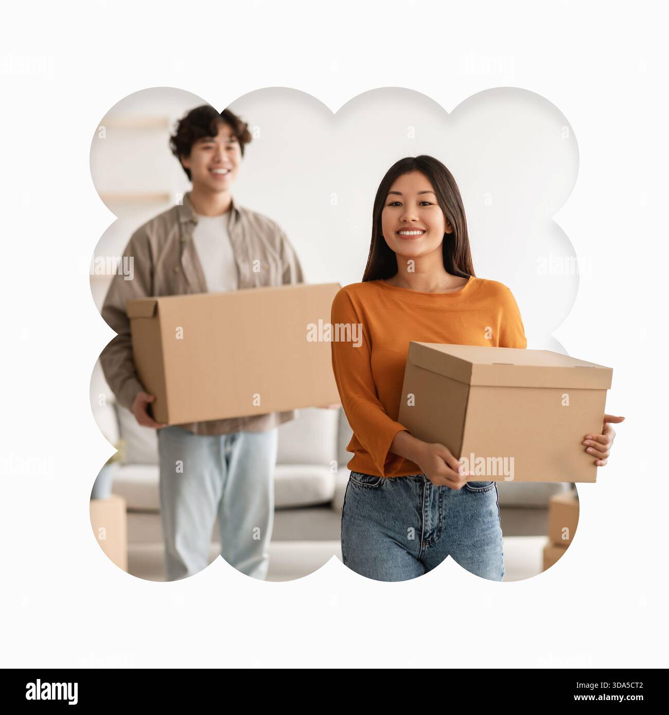 Ein Paar trägt Kisten, während er in ein neues Zuhause in einem hellen und einladenden Raum zieht Stockfoto