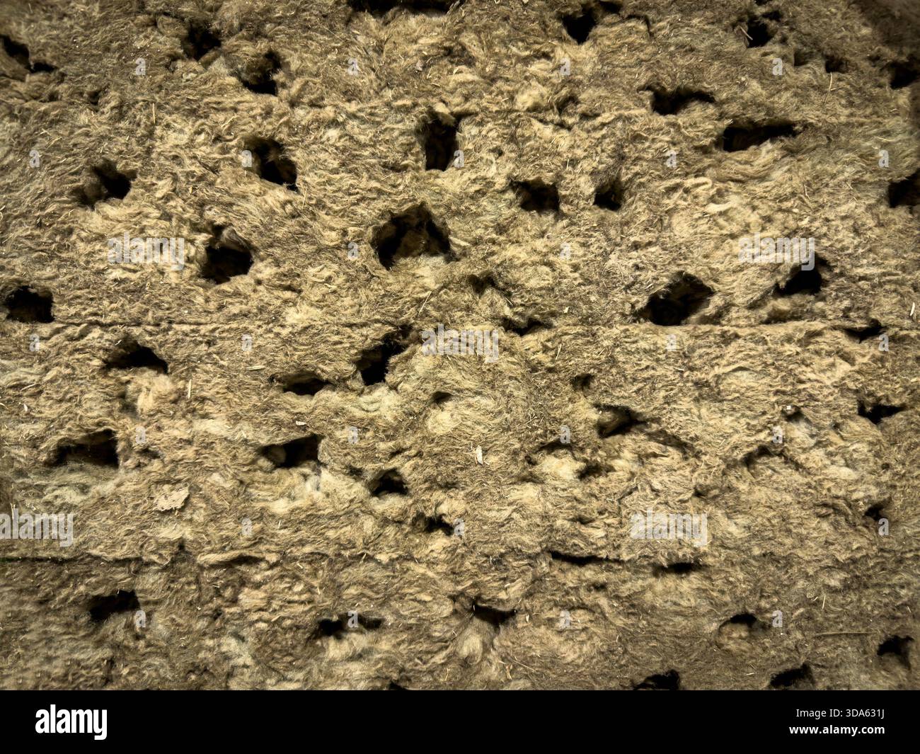 Nahaufnahmetextur von Mineralwolle-Isolierung, Steinwolle oder Steinwolle. Die faserförmige, perforierte Oberfläche zeigt die Art des verwendeten thermischen und akustischen Materials Stockfoto