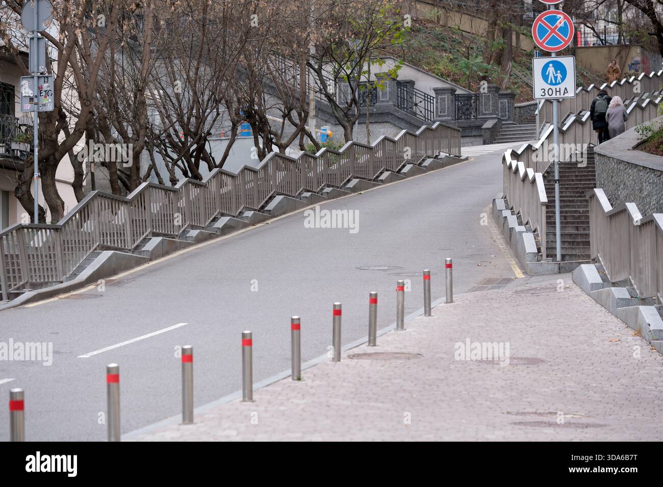Eine ruhige, gewundene Straße ist gesäumt von charmanten Geländern und Bäumen. Stockfoto