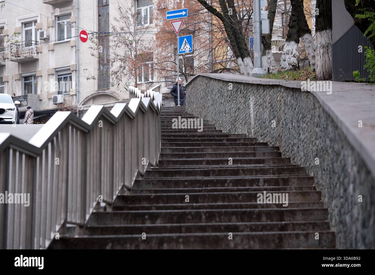Geschwungene Stufen führen zu einer belebten Straße, die von urbaner Architektur eingerahmt ist. Stockfoto