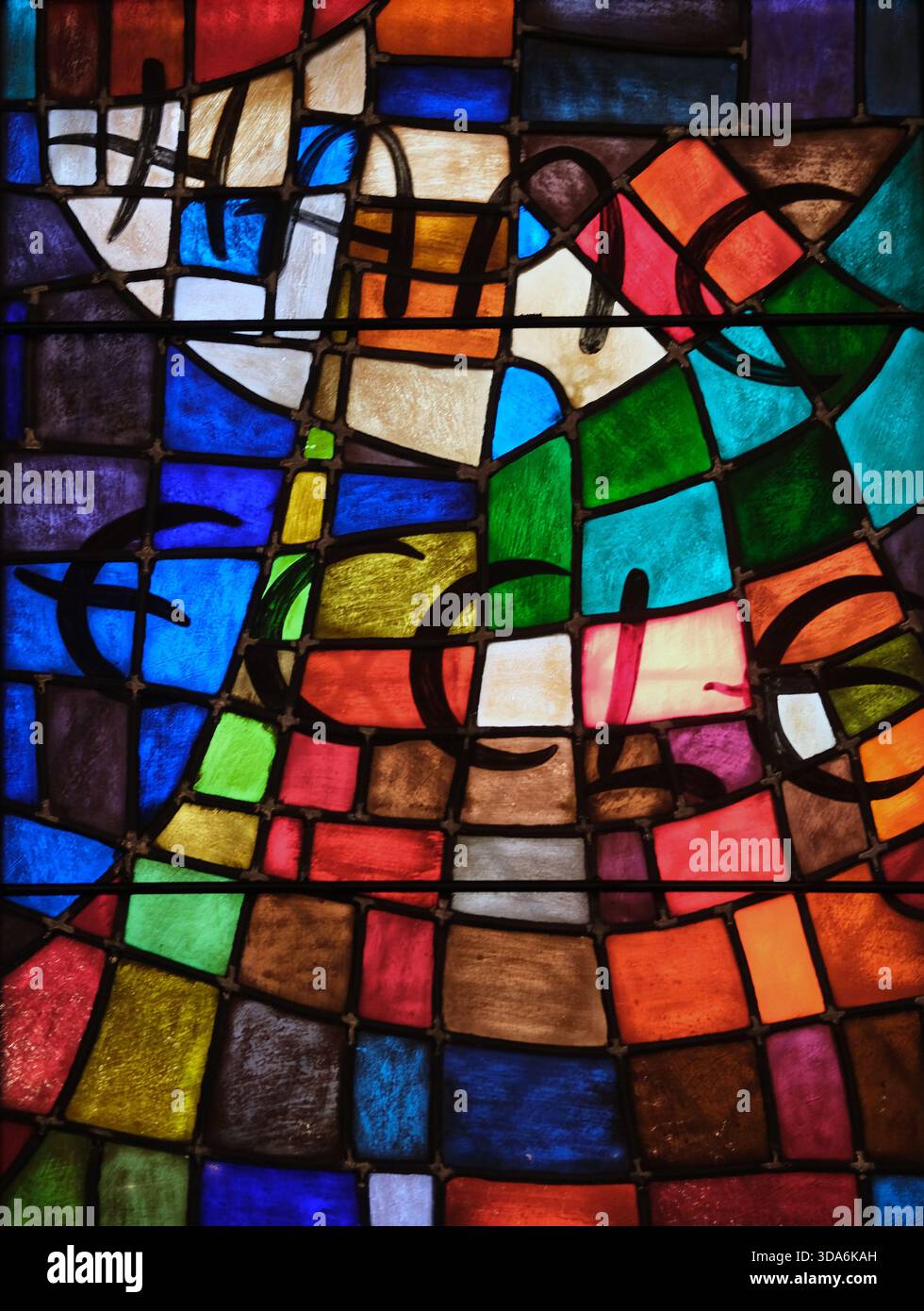 Nahaufnahme eines Buntglasfensters aus unregelmäßigen geometrischen Glassegmenten in blau, rot, grün, gelb, orange, weiß und violett. Stockfoto