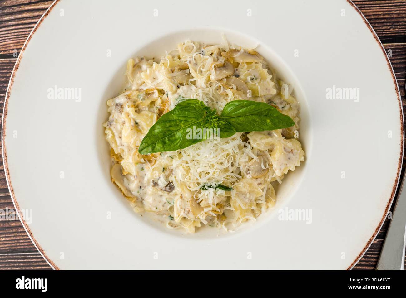 Cremige Pilznudeln mit geriebenem Parmesan und frischem Basilikum Stockfoto