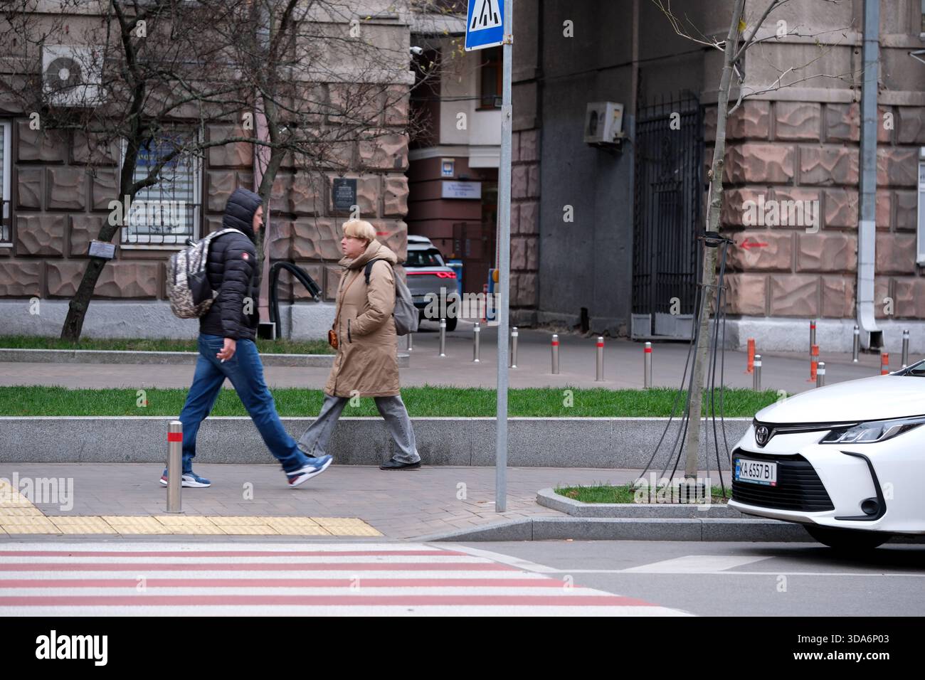 Im Herbst schlendern zwei Personen auf einer lebhaften Stadtstraße an einander vorbei. Kiew, Ukraine. Dezember 2025. Stockfoto