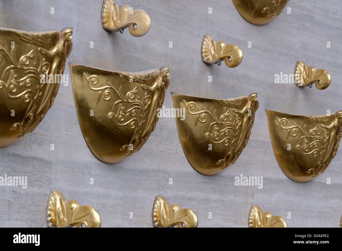 Goldene Schilde schmücken eine strukturierte Wand, die künstlerische Handwerkskunst zeigt. Kiew, Ukraine. Dezember 2025. Stockfoto