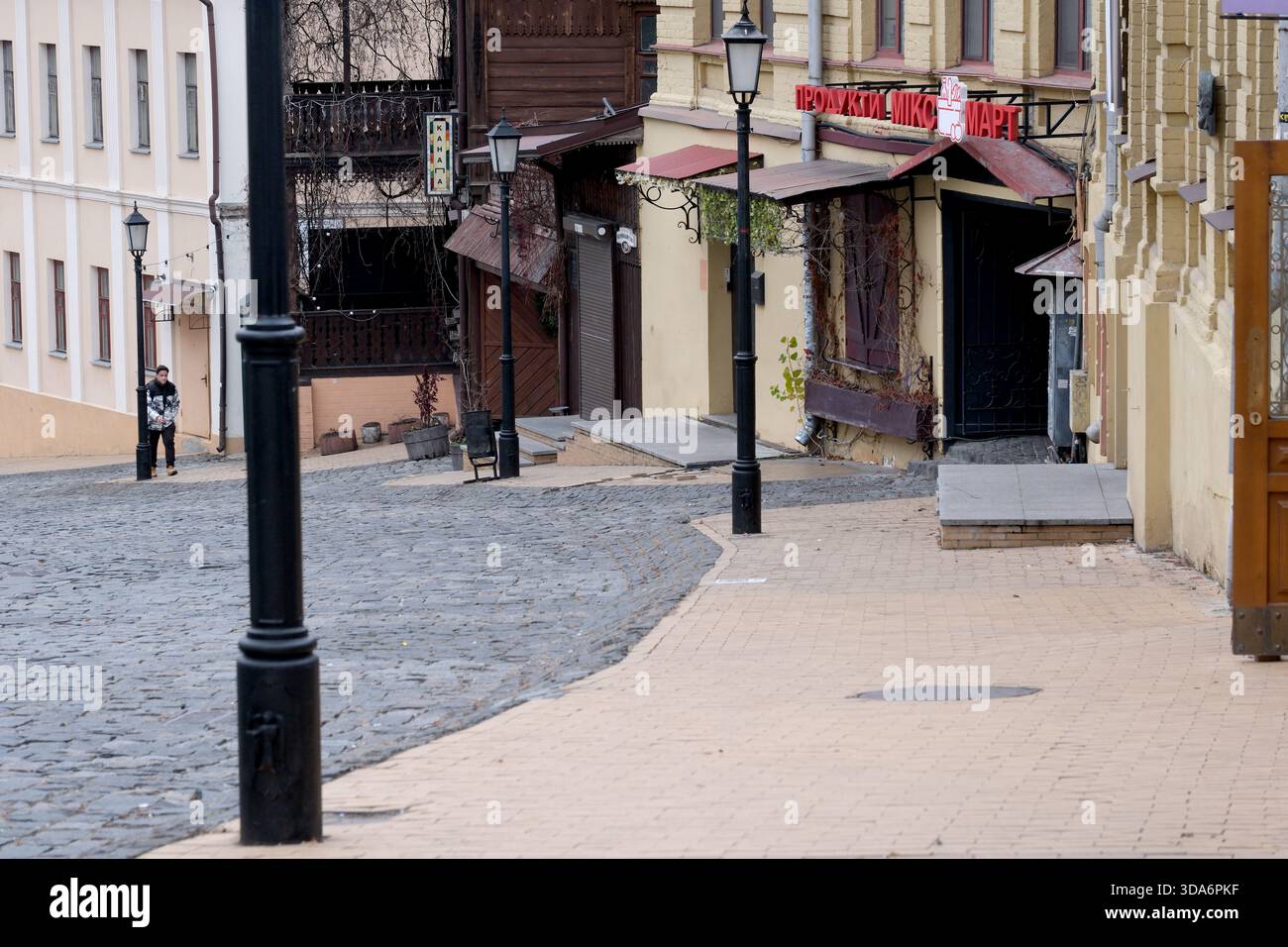 Eine ruhige, geschwungene Straße führt zu einer einladenden Tür, die Entdeckungen verspricht. Andrejewski Uzviz, Kiew, Ukraine. Dezember 2025. Stockfoto