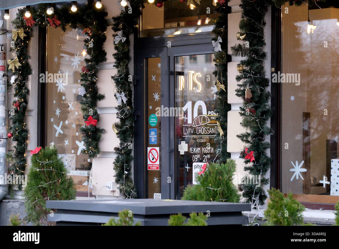 Einladende Bäckerei, dekoriert mit Girlanden und Lichtern in einer winterlichen Umgebung. Podil, Kiew, Ukraine. Dezember 2025. Stockfoto