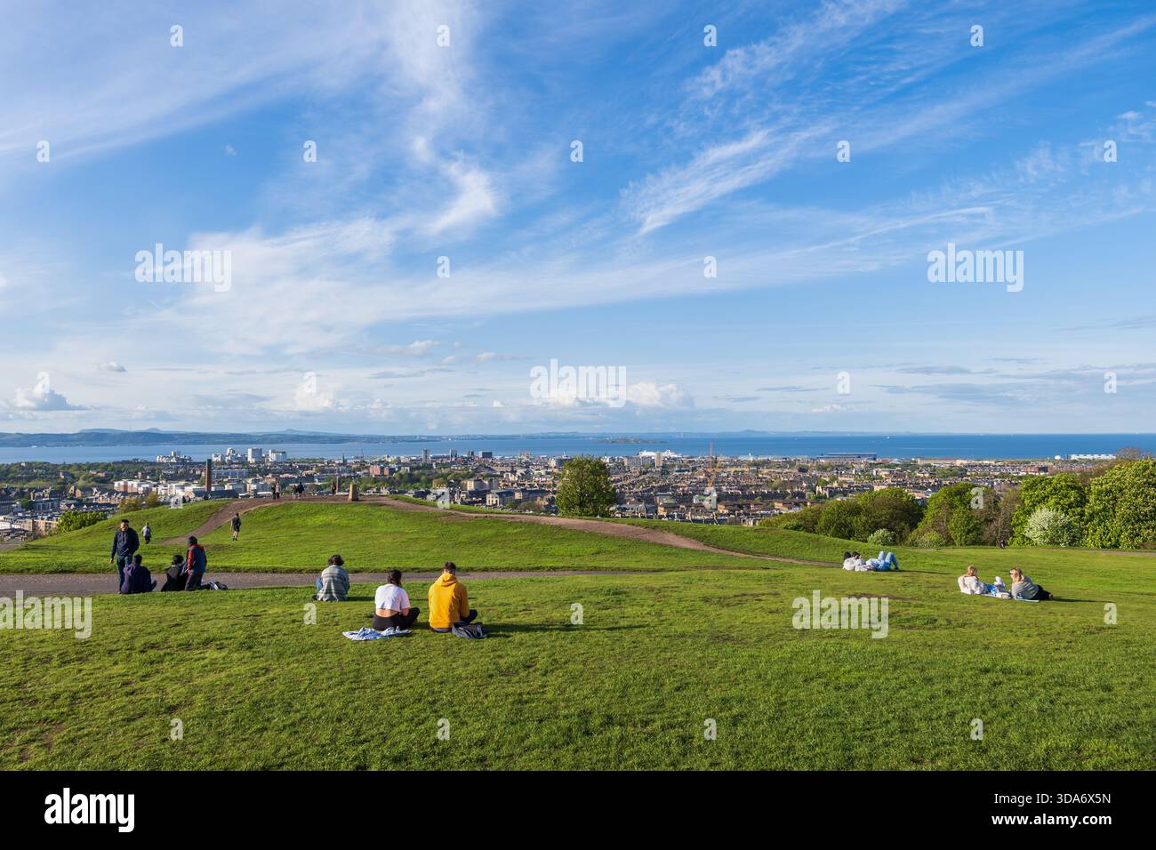 Edinburgh, Schottland, Vereinigtes Königreich - 9. Mai 2023: Calton Hill mit Blick auf die Stadt und Menschen, die sich am Frühlingsnachmittag auf dem Gras entspannen. Stockfoto