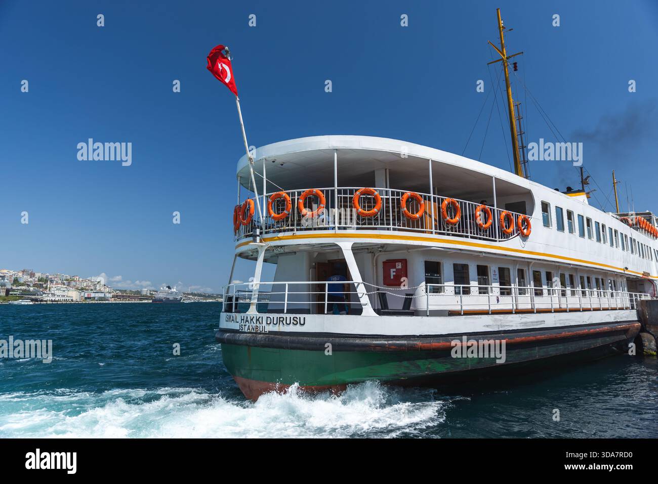 Istanbul, Türkei - 23. August 2025: Eine Passagierfähre befindet sich am Hafen von Istanbul unter klarem blauem Himmel. Orangene Rettungsschirme säumen die Schiene, türkisch Stockfoto