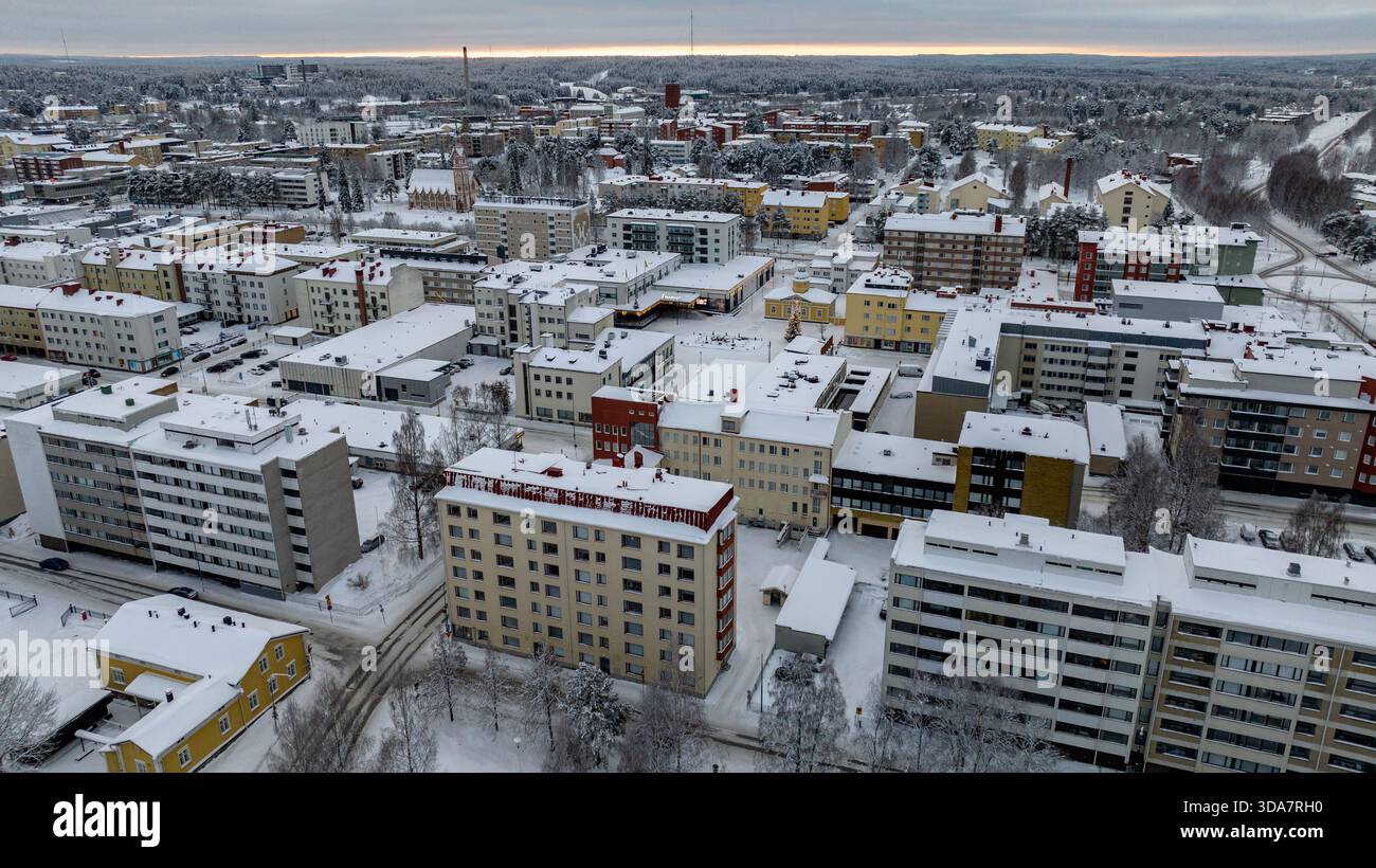 Aus der Vogelperspektive von Gebäuden mit schneebedeckten Dächern stehen in krassem Kontrast zum gedämpften Himmel, einer Wintergeschichte, die sich über der urbanen Landschaft entfaltet: Kajaani, Stockfoto