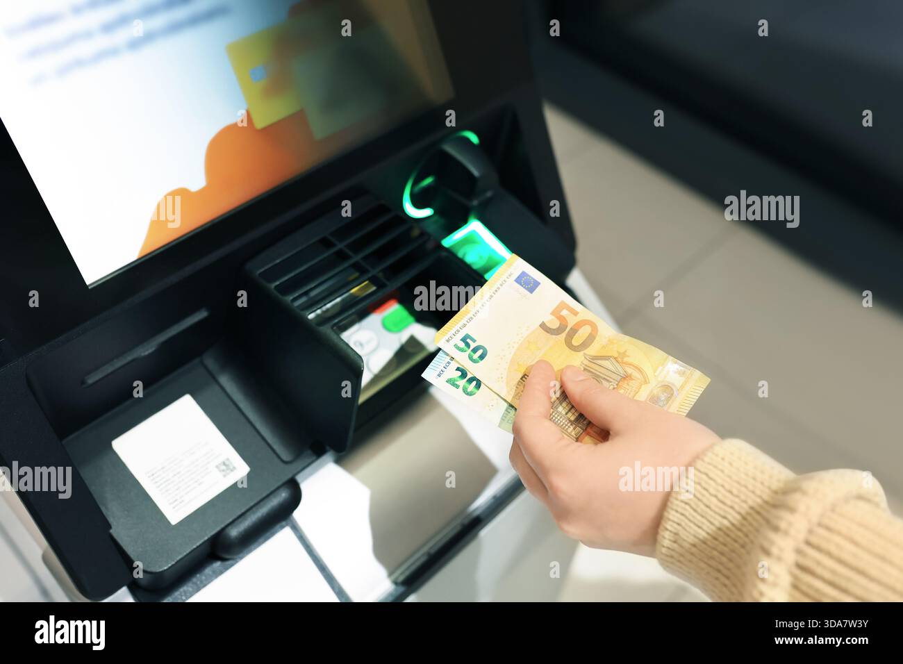 Frau, die Euro-Banknoten am Geldautomaten hält. Hand mit 50 und 20 Euro Bargeld in der Nähe des Bankterminals. Hochwertige Fotos Stockfoto