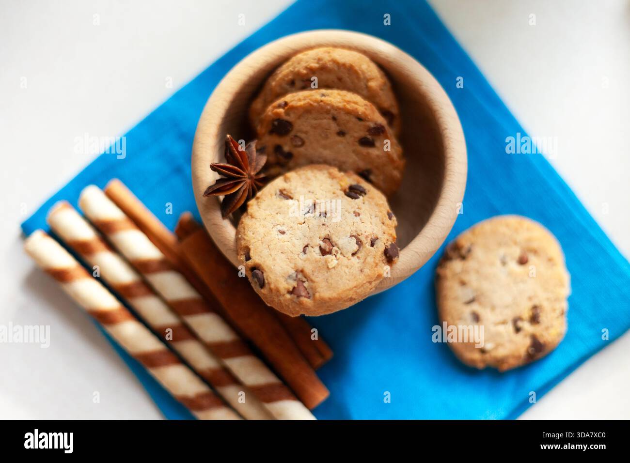 Schokoladenkekse in einer Holzschale mit Anis- und Waffelstäbchen und Zimt daneben, Blick von oben Stockfoto