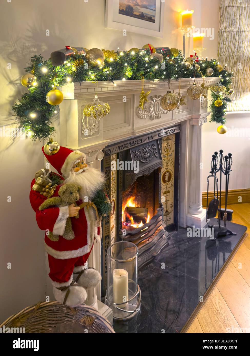 Ein traditioneller Kamin und Kaminsims, dekoriert für Weihnachten mit einer Girlande und Feenlichtern in einem Wohnzimmer Stockfoto