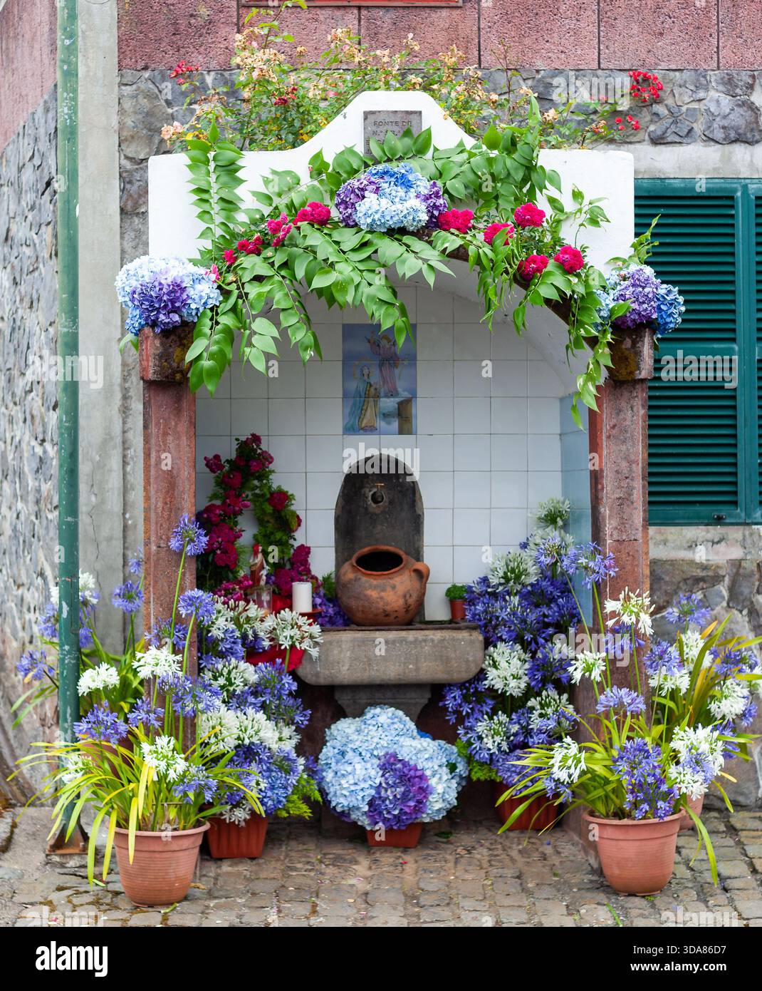 Traditioneller Wasserhahn mit leuchtenden Blumen auf Madeira, Portugal. Stockfoto