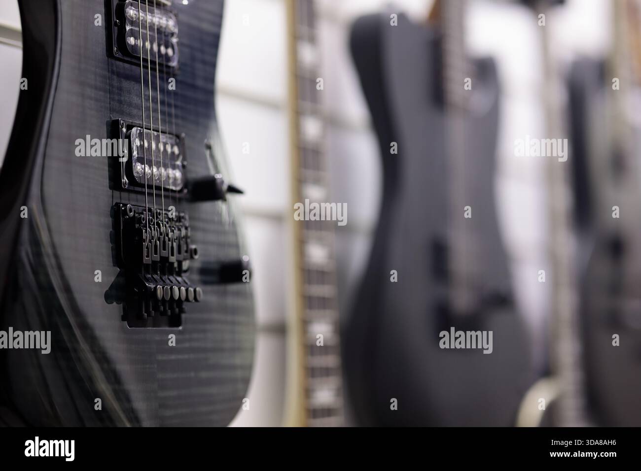 Schwarze E-Gitarren hängen an einer Wand im Musikgeschäft. Selektiver Fokus. Stockfoto