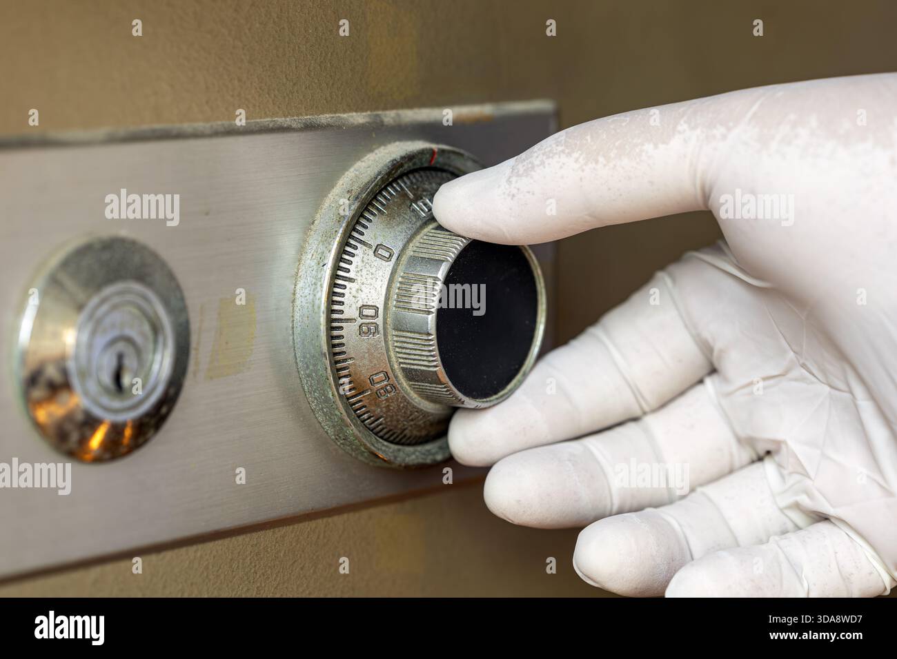 Eine Nahaufnahme einer Hand mit weißem Handschuh, die das Kombirad an einem Metallschloss dreht, um die Sicherheit und den sorgfältigen Umgang mit Wertsachen hervorzuheben. Stockfoto