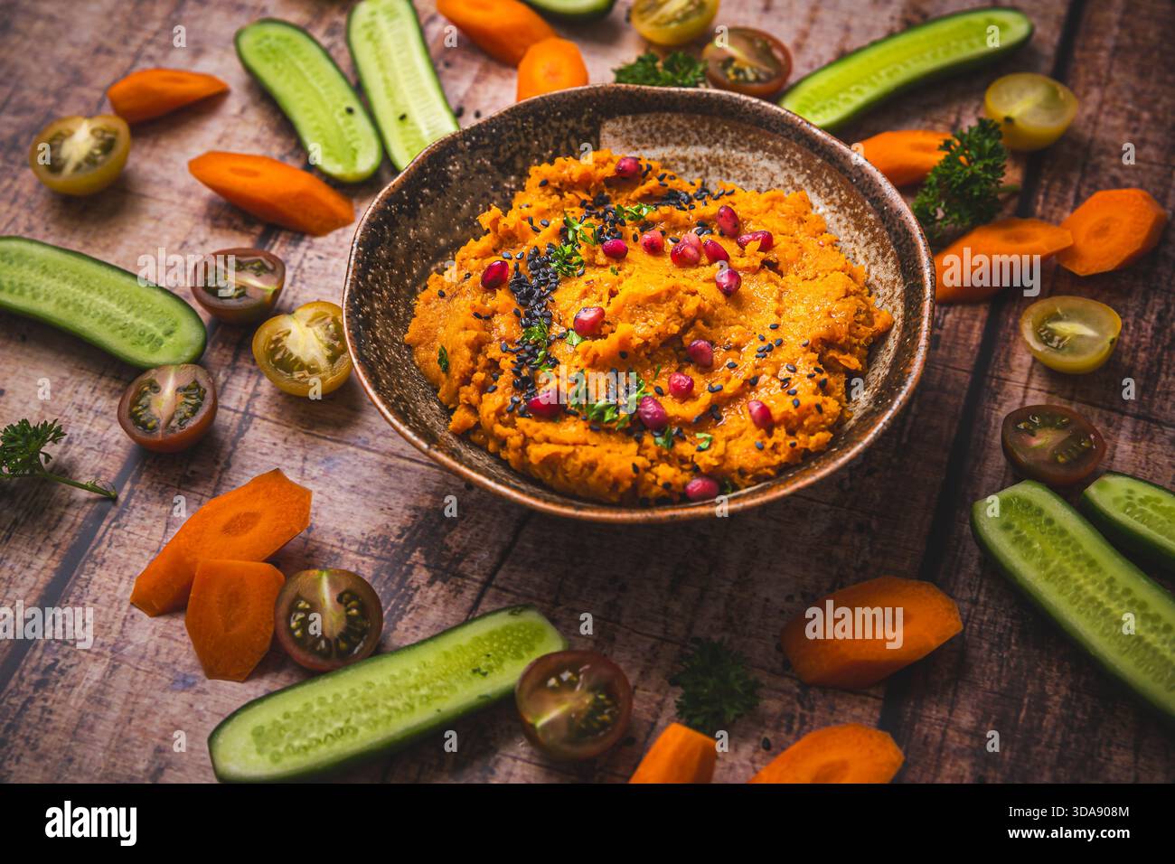 Würziger Karotten-Hummus mit rohen Gemüsestäbchen Stockfoto