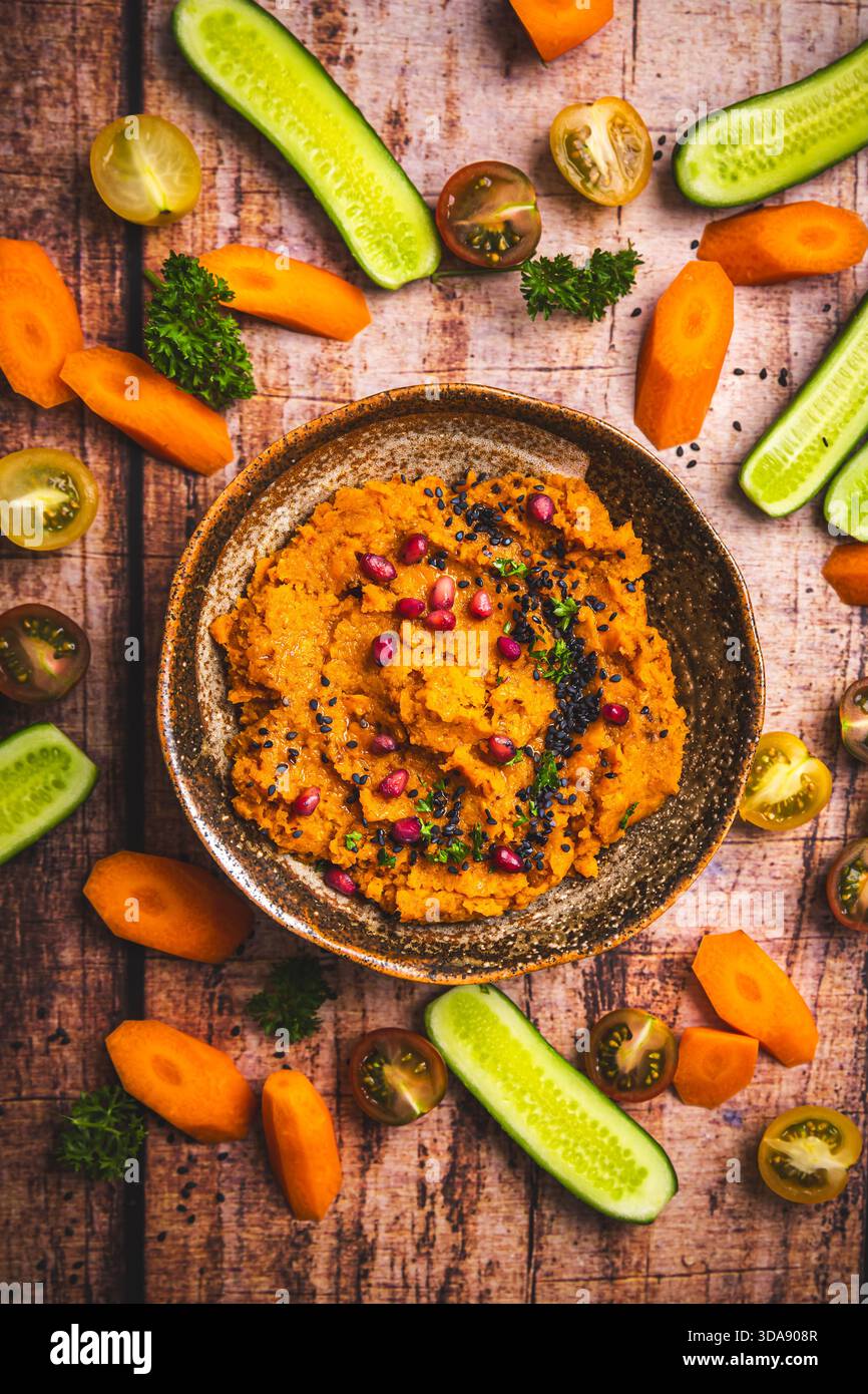 Würziger Karotten-Hummus mit rohen Gemüsestäbchen Stockfoto